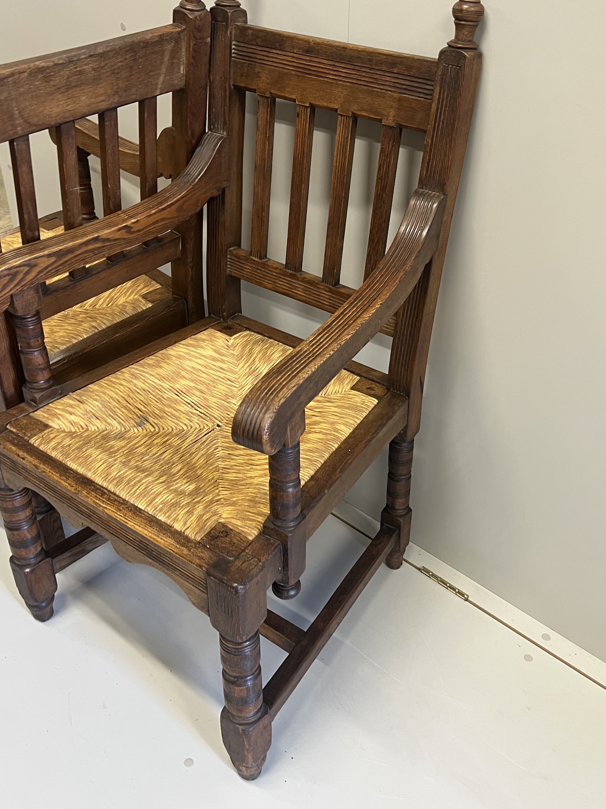 A pair of Victorian Arts & Crafts oak rush seat elbow chairs, width 58cm, depth 54cm, height 104cm